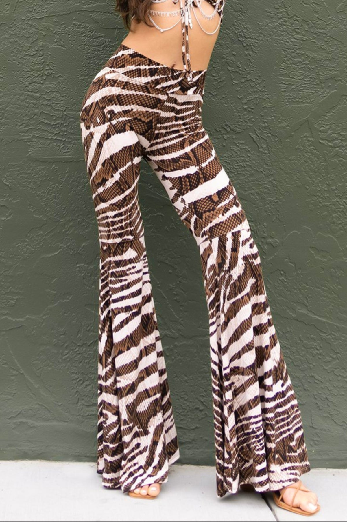 A model wearing a brown and ivory animal print outfit, consisting of a top and bell-bottom pants.