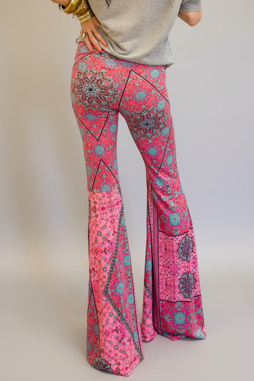 Person wearing pink patterned boho bell-bottom pants on a grey background